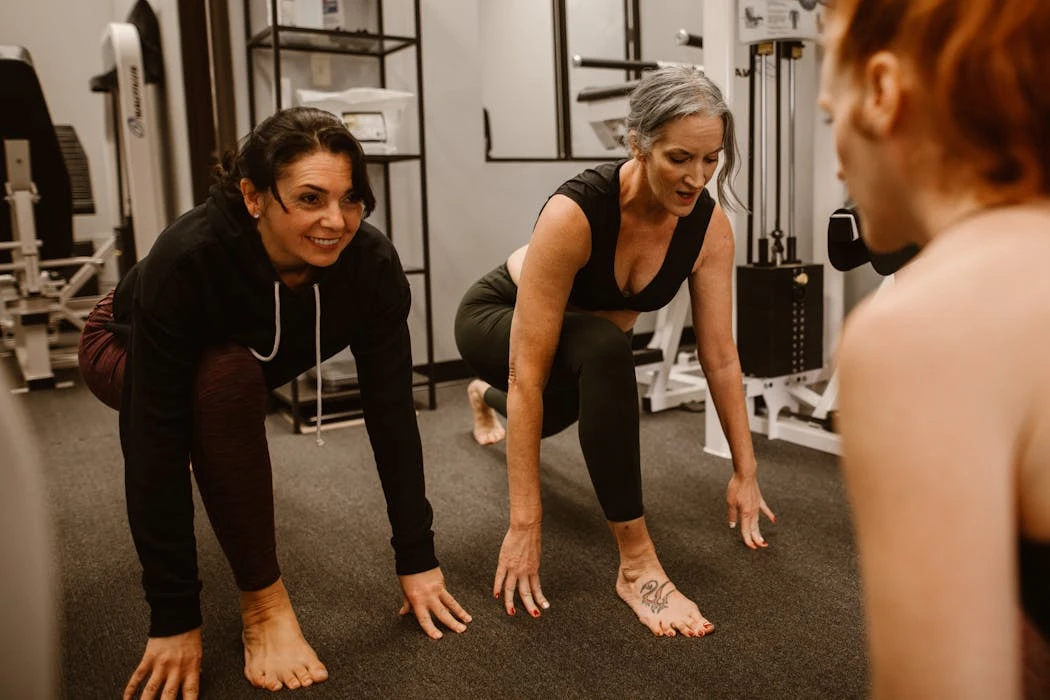 Three women engaged in a workout session in a gym, focusing on strength and balance.